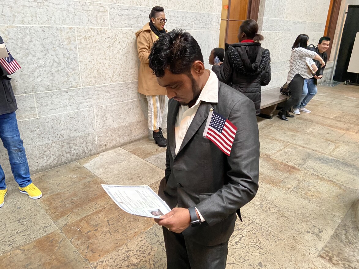 Man Biswa looks at the certificate he received at the naturalization ceremony. (credit Kasler)